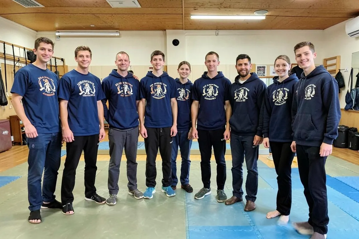 Kampfsportgruppe in einheitlichen Club-T-Shirts und Hoodies mit Vereinsemblem im Trainingsraum