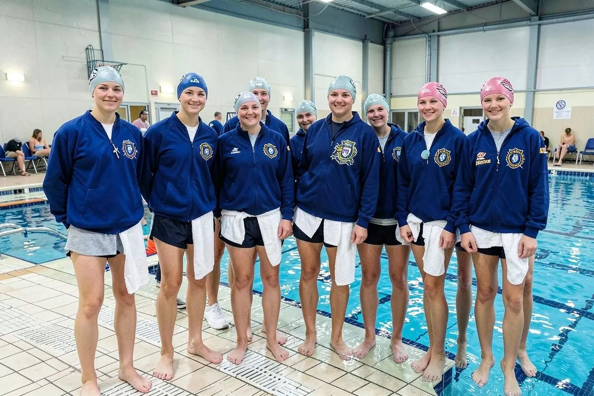 Schwimmteam in einheitlichen Teamjacken mit Vereinsemblem am Beckenrand einer Schwimmhalle